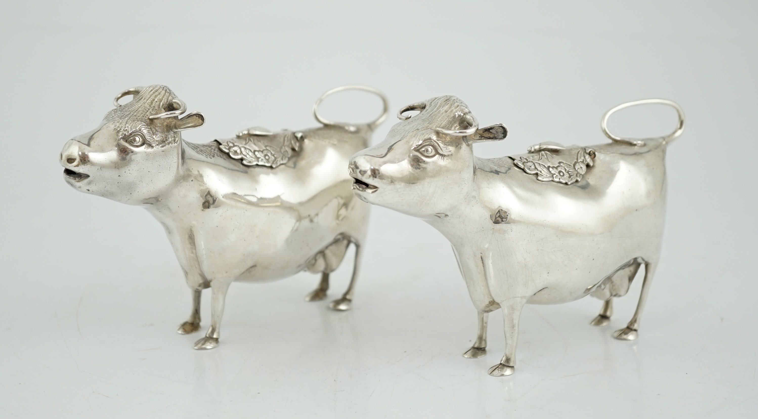 A pair of Elizabeth II silver cow creamers, by Heming & Co